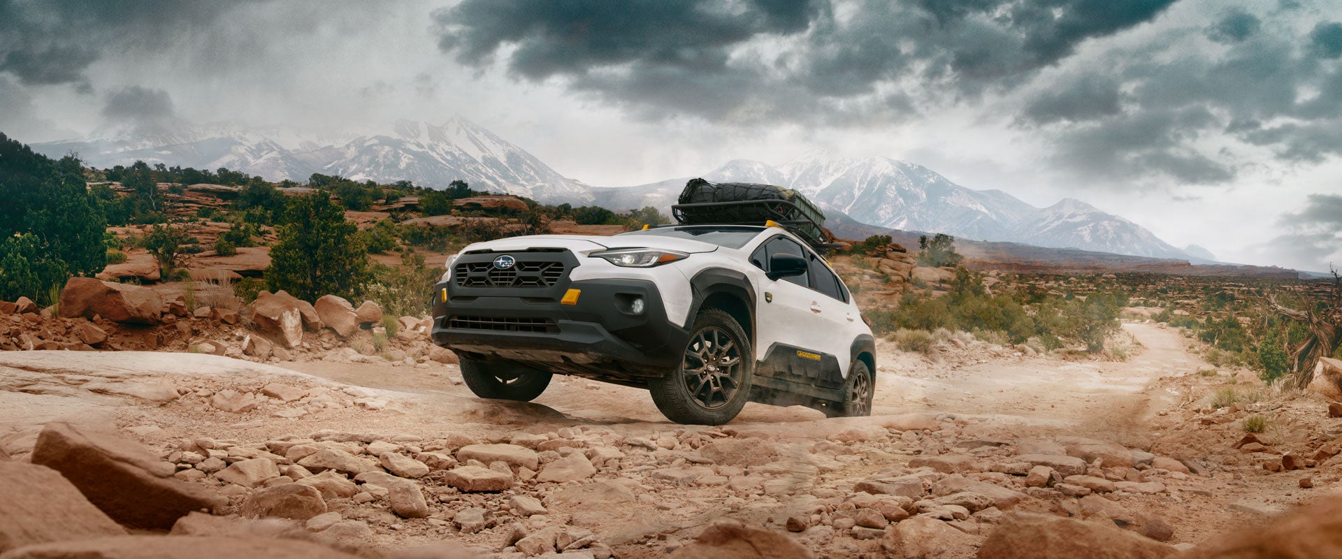 A white Crosstrek Wilderness drives up a rocky canyon